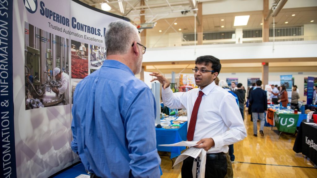 Image of a student explaining a poster to someone at an event.