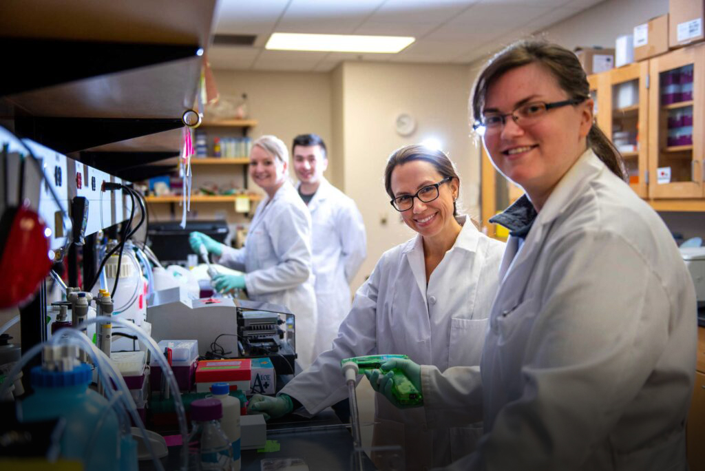 four people smiling in lab setting