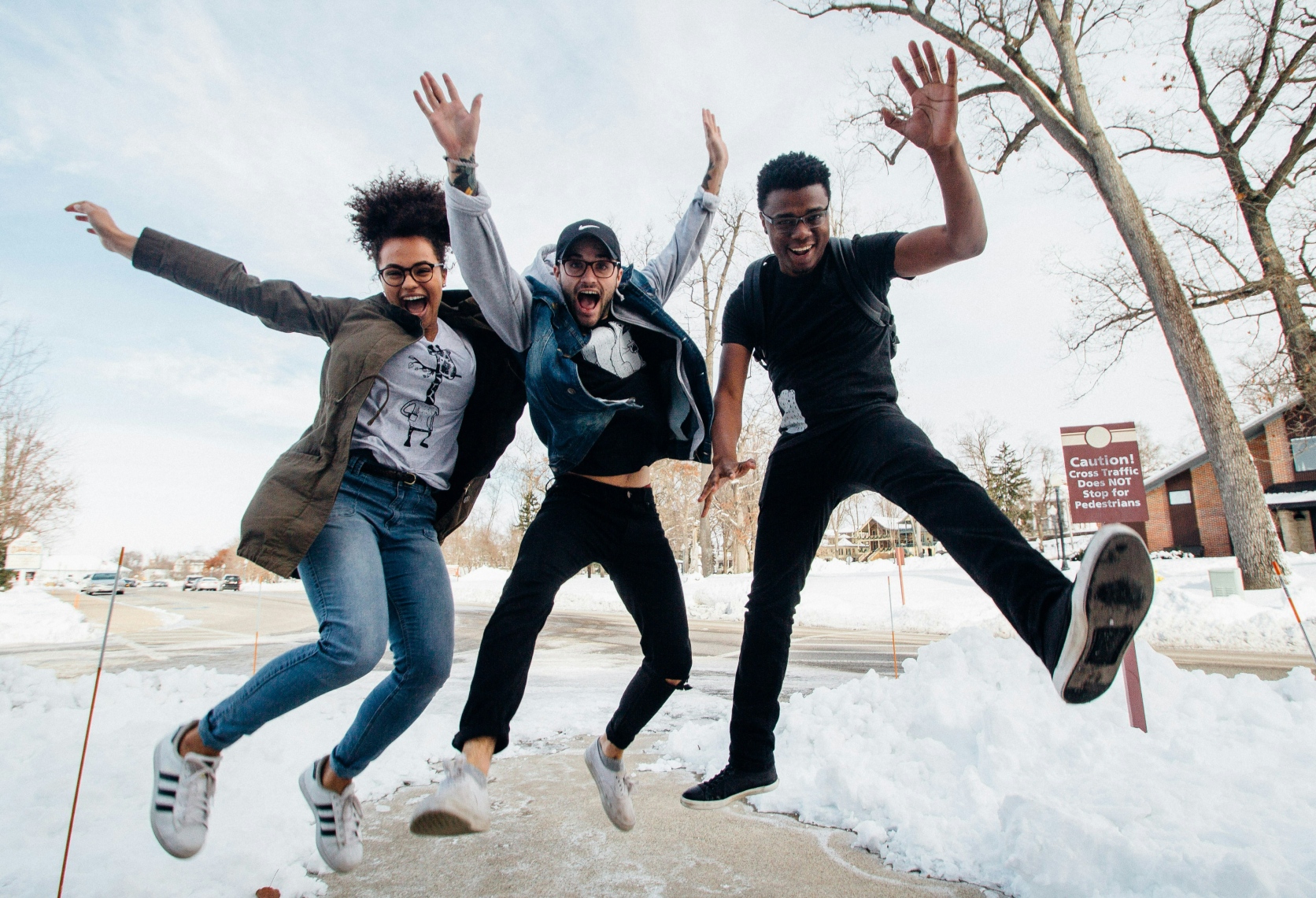three people jumping outdoors on a snowy day