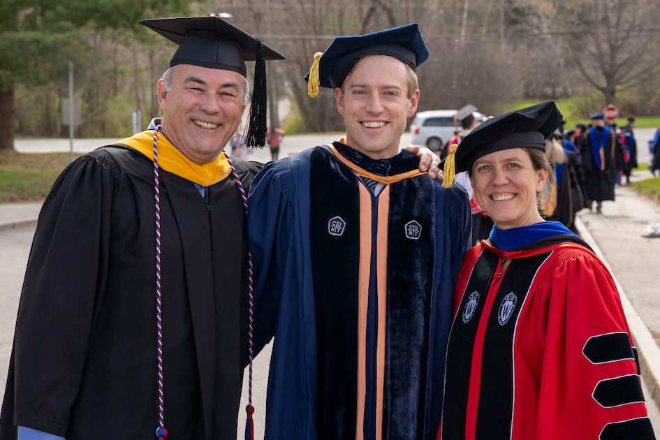 Image of three individuals wearing academic regalia