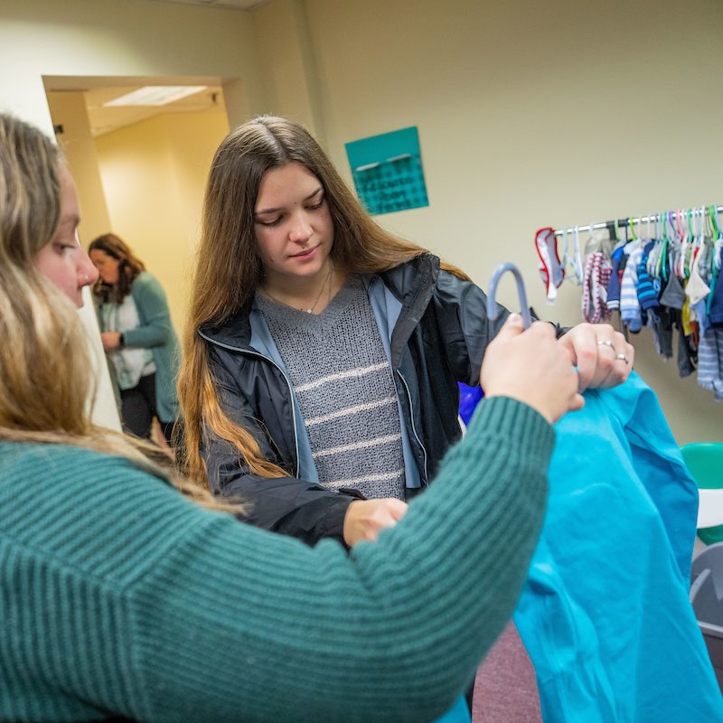 two people looking at a baby's onesie on a hanger