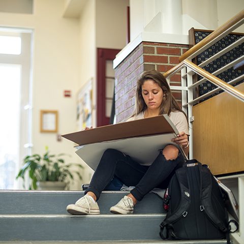 student sitting on steps and drawing