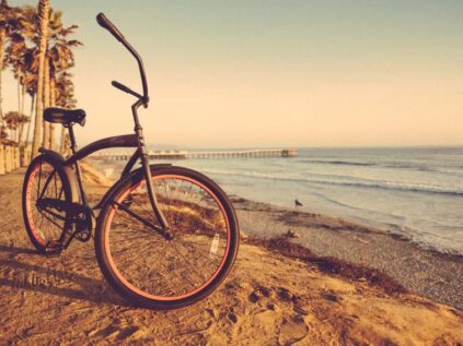 Photo of a bike on the shore of the ocean at sunset