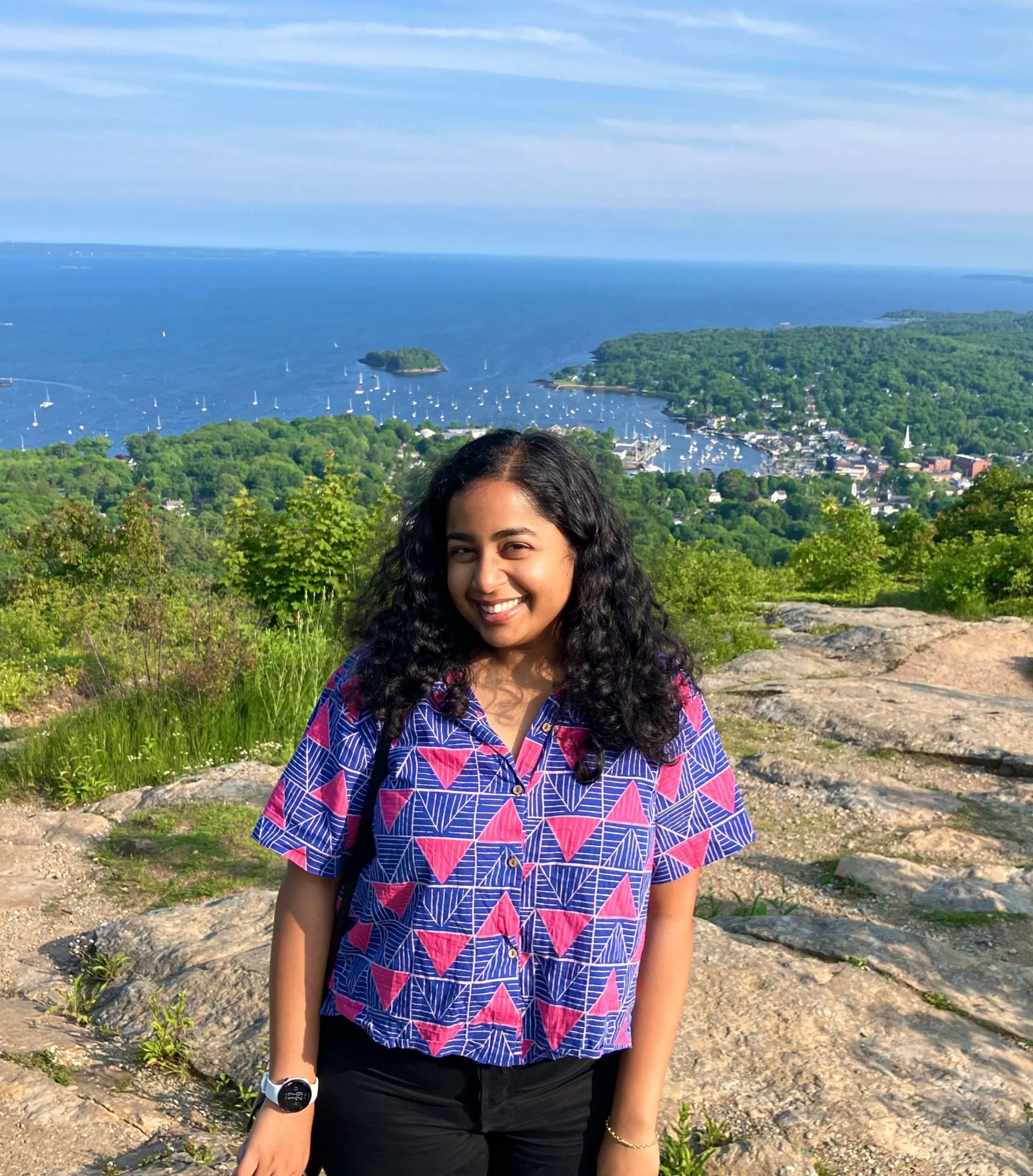 Image of Soumya Gupta standing in front of a coastal landscape