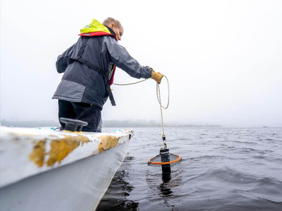 A photo of Lauren Ross lowering a piece of equipment into water