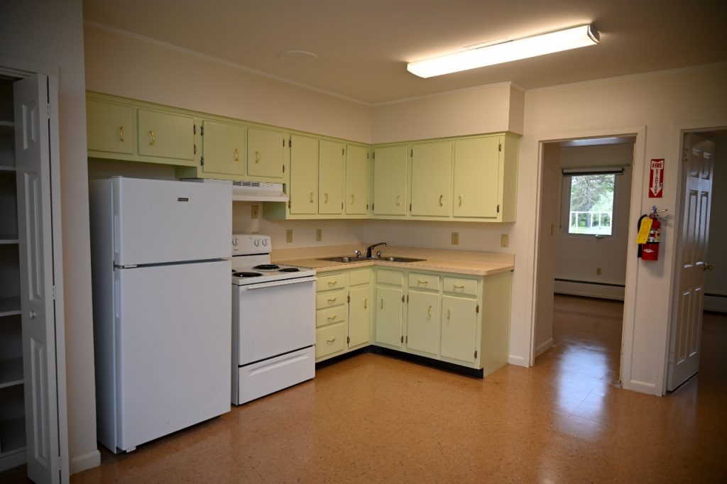 Kitchen featuring pale green cabinets, a white refrigerator, a white stove, and doorways.