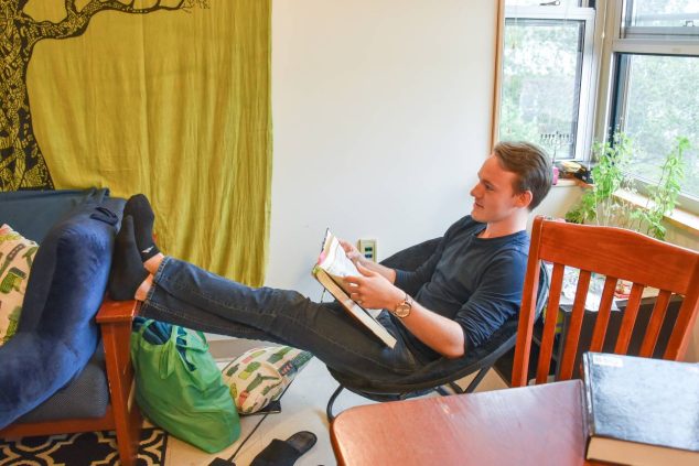 A student sitting in a chair with their feet propped up, reading a book.