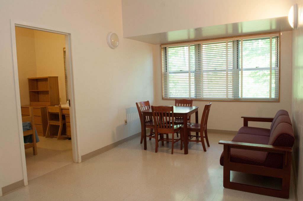 Living area with a wooden table, four chairs, a sofa, and an open doorway.