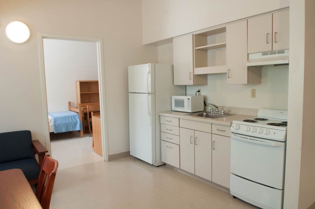 Kitchenette area with white appliances and an open doorway leading to a bedroom.