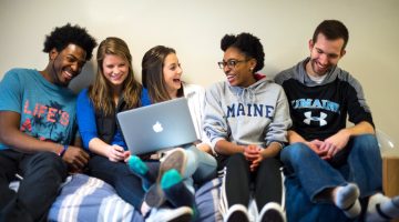 A photo of a group of students sitting around a laptop