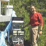 A researcher from Howland Forest next to a devices to measure biogeochemical inputs