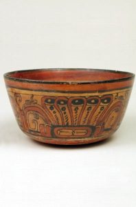 A brown bowl incised and painted with swirling designs.
