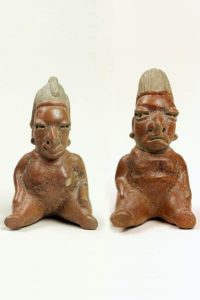Two painted ceramic figurings with detailed faces.
