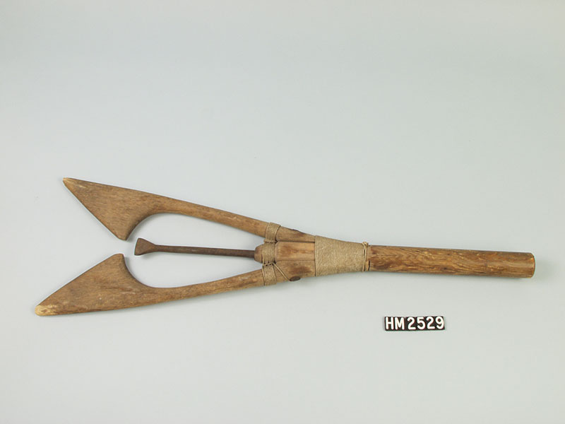 The business end of a fishing spear with a central spike flanked by wooden wings designed to keep the fish from slipping off.