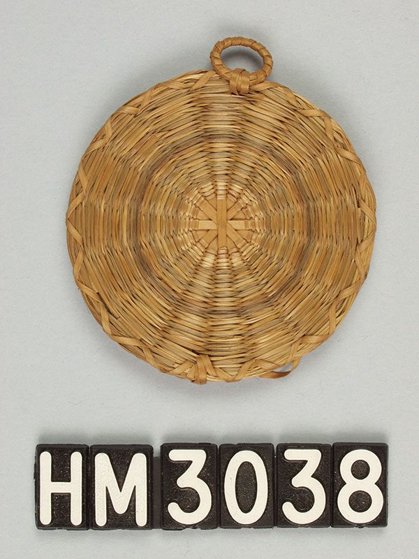 Small circular object woven with single strands of grass.