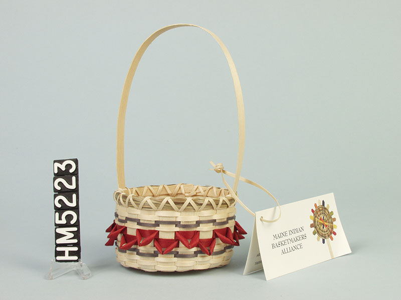 Image of small basket with red points and a thin handle.