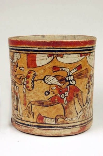 Vase with vertical sides. Orange slip under red, black, white, and brown on the exterior. The rim is encircled with a red, orange, black, white, black, orange, and black bands and the base has the bands in reverse order. Between is a figure seated in the tailor position facing to the left. This figure has his right arm extended out in gesture to the standing figure. The seated figure wears a headdress with water lily extension and has either a pillow or bundle wrapped in jaguar skin at his back. The figure is seated underneath a draped ceremonial banner and is represented in conversation with speech glyphs.