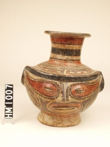 Cocle polychrome ceramic effigy jar. Parita type, Ortiga variety. Effigy head with red painted mask around eyes, tall spout with red and black rings. Conte or Macaracas. Significance of effigy heads not clear. The claws above the forehead may identify this creature as an animal. The back is decorated with a Y-element, whose tail is an iguana-boa head with an open mouth and teeth, horizontal eye slits and eye stripes. Therefore, the effigy may be an anthropomorphic form of the iguana-boa.