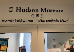 Image of the text above the maine entrance to the Hudson Museum showing the Penobscot word for 's/he reminds h/her'.