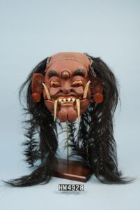 Image of a fearsome looking mask with fangs and hair