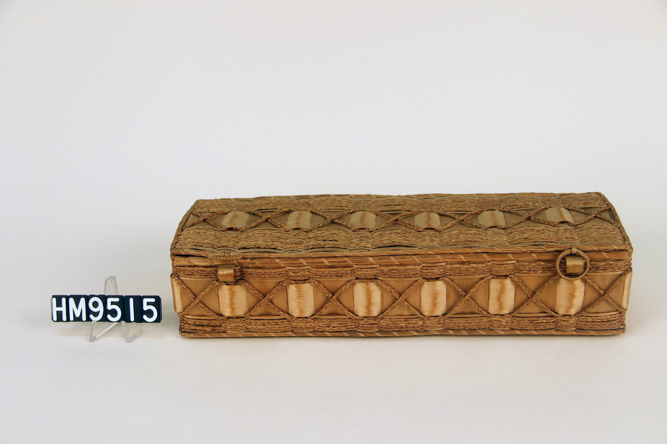 Image of a long, rectangular box with shiny ribbonwork and braided sweetgrass details.
