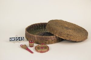 An opened up braided sewing basket with red accented sewing notions included.