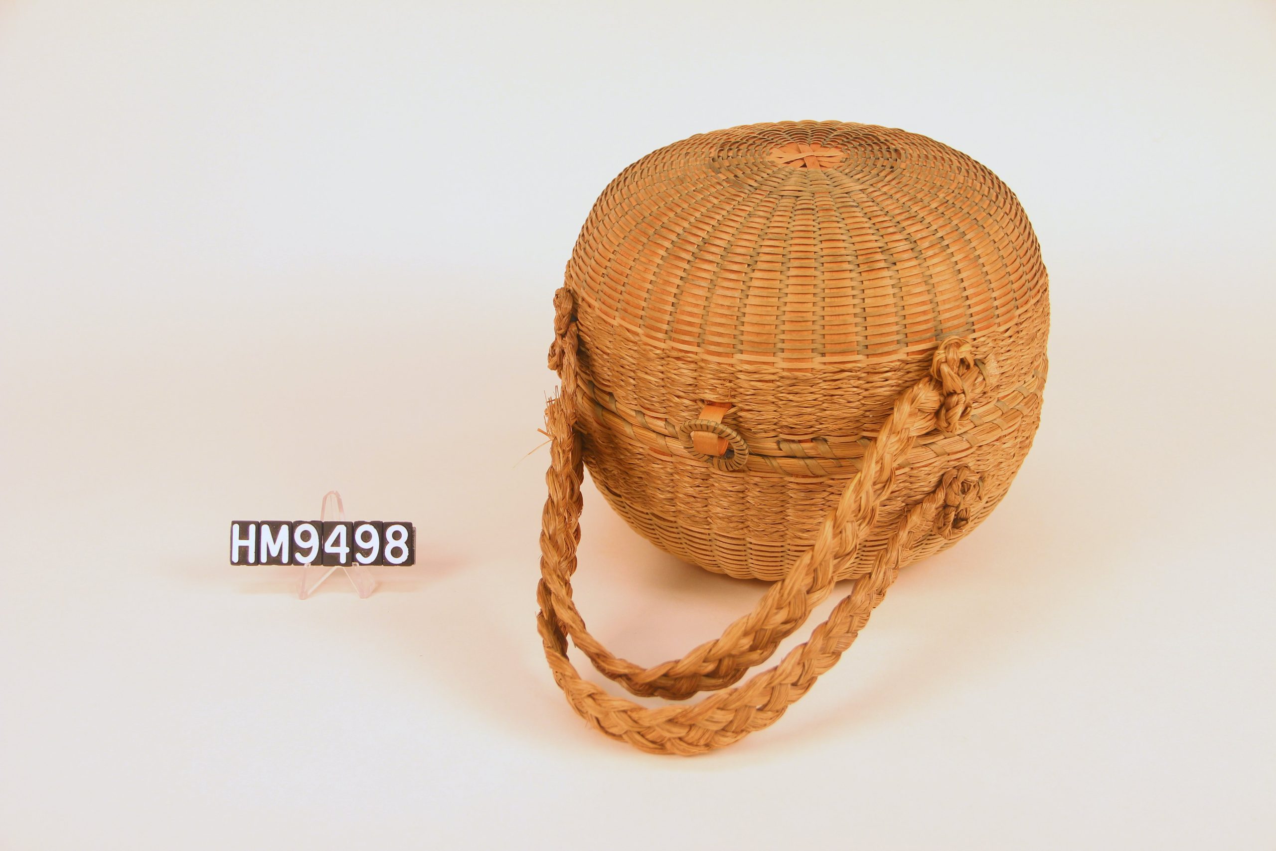Image of a basket purse - round in shape with braided sweetgrass handles