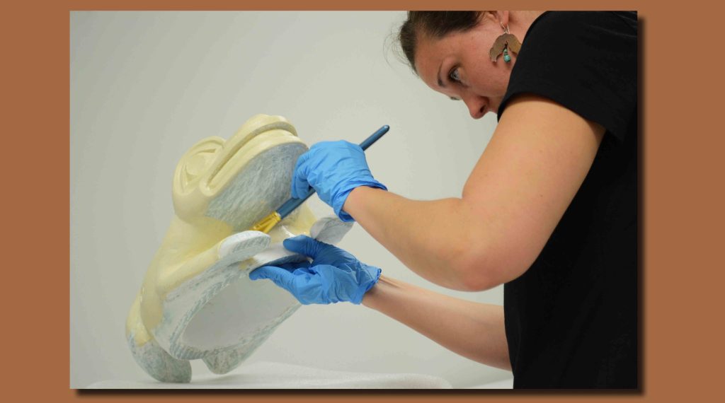 Image of Anna Martin applying a base layer of paint to the replica. 