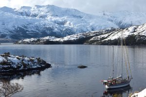 sailboat in front of a show covers mountain