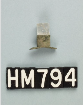 Image of a small ornament with a crystal set into the top and the bottom flaring to a T.