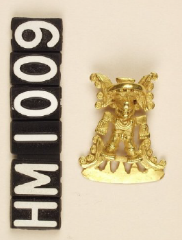 Image of small gold ornament in form of figure with face of bat and wearing large, ornate headdress.