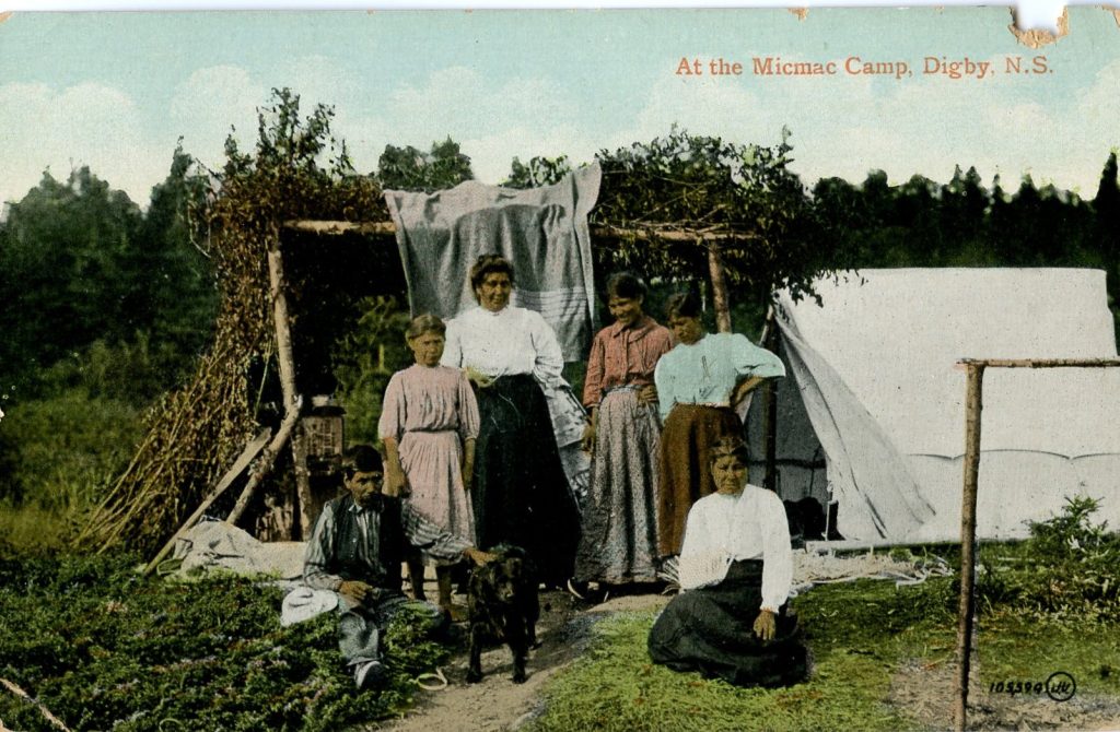 Colorized image of six people and a dog by a canvas tent and wood-and branch structure. The people wear European-style clothing. Basketmaking materials can be seen around the group.