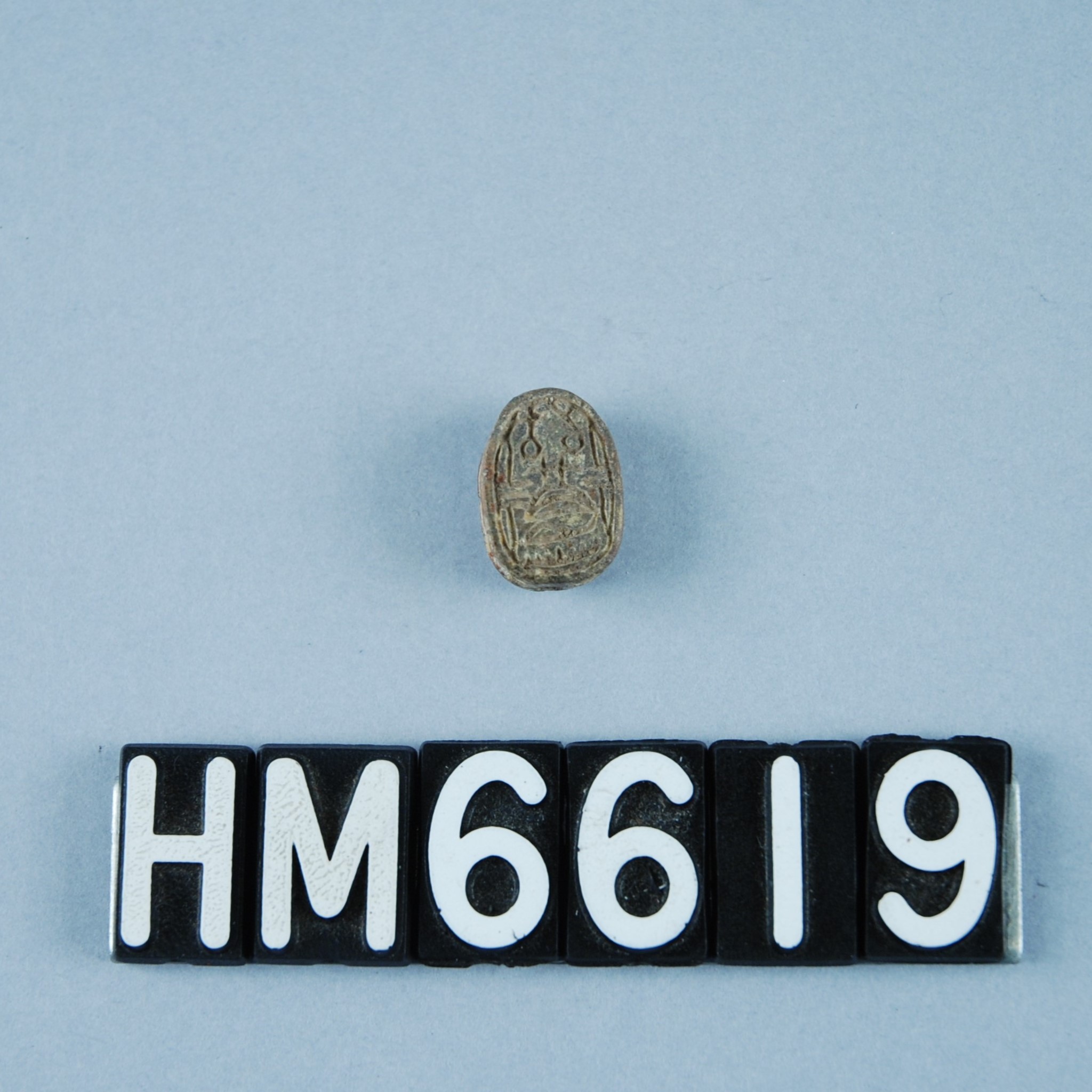 Image of a tiny oval stone carved with an intricate design.