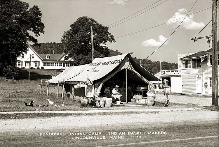 Black and white image of a canvas tent along a road. The tent reads "Indian Baskets"