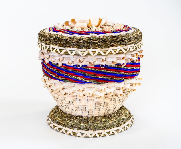 Image of a decorative basket with curls, finely-braided sweetgrass, and stripes in blue and magenta.