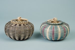 Two miniature urchin baskets. One has dark and light stripes and the other is tan, blue, and purple.