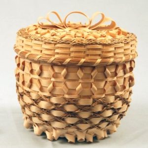 A decorative basket in natural colors with braided sweetgrass and ash curls.