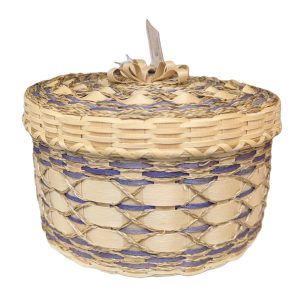 A large, decorative basket with wide weavers, braided sweetgrass decorations, and lavender details.