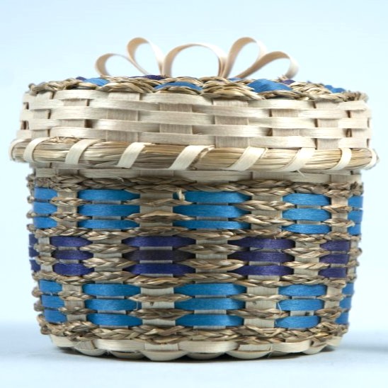 A basket with sweetgrass braids and brown ash in shades of blue.
