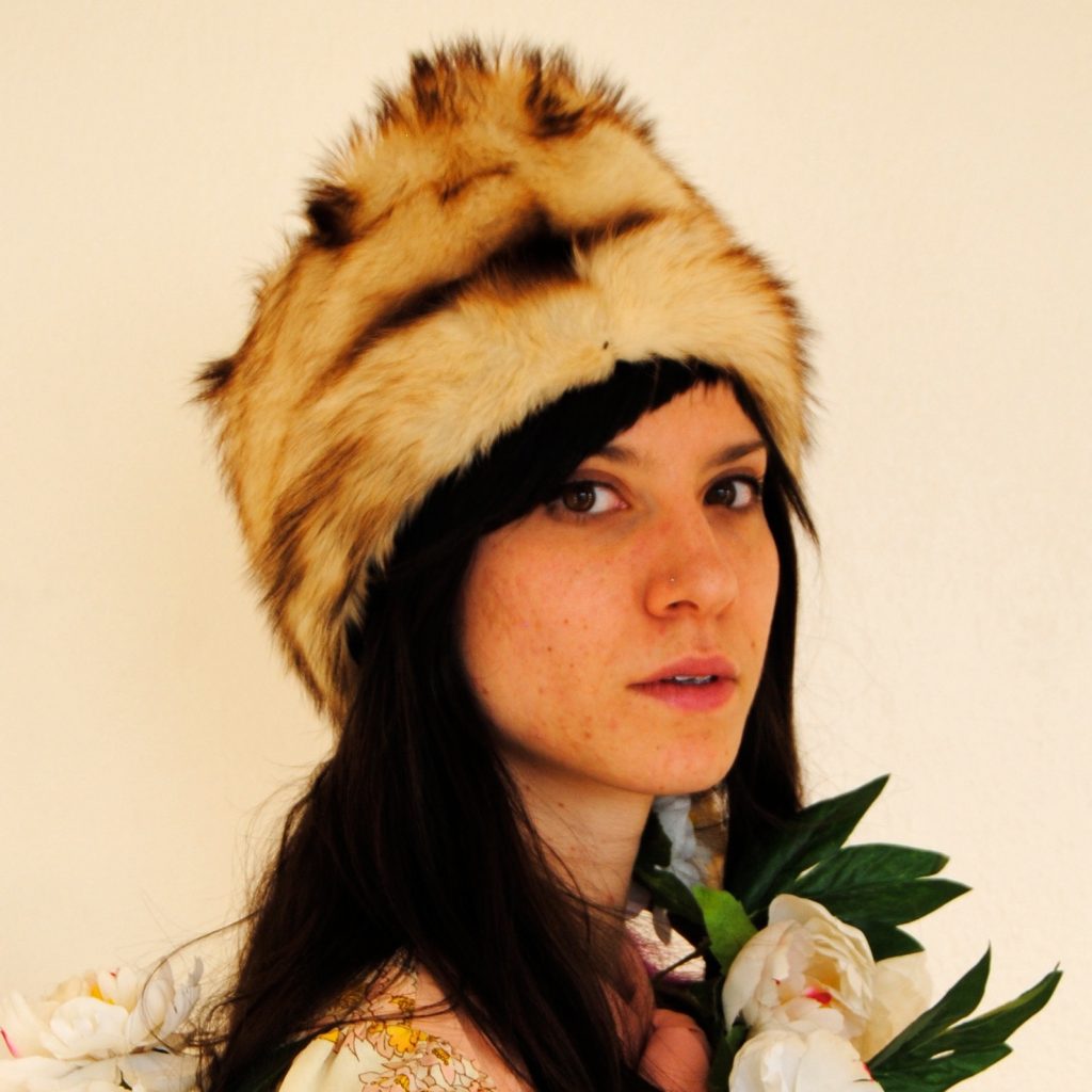 Image of Caucasian woman with dark hair wearing fur cap and shirt with flowers.