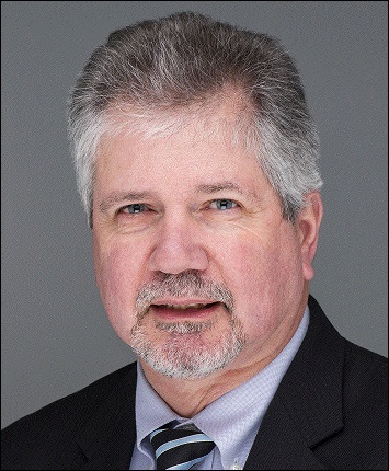 Portrait of Caucasian man with gray hair and neat goatee wearing a suit and tie.
