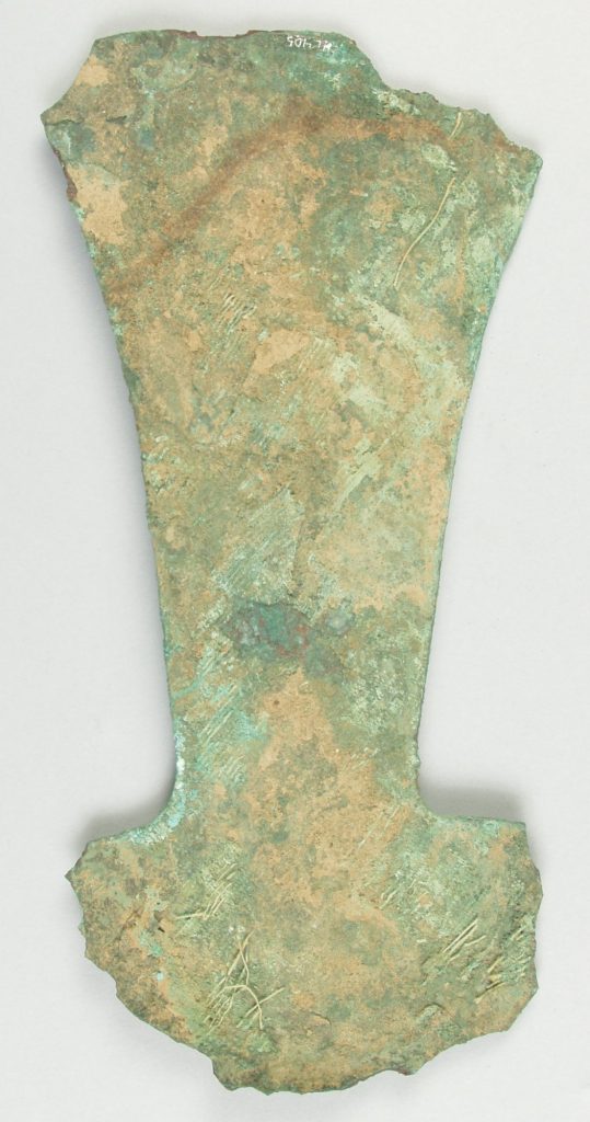 Pale green object with ragged borders and fabric threads attached to surface.