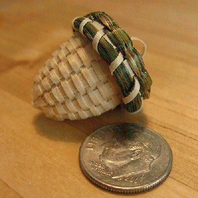 Image of tiny acorn-shaped basket next to a quarter for scale.