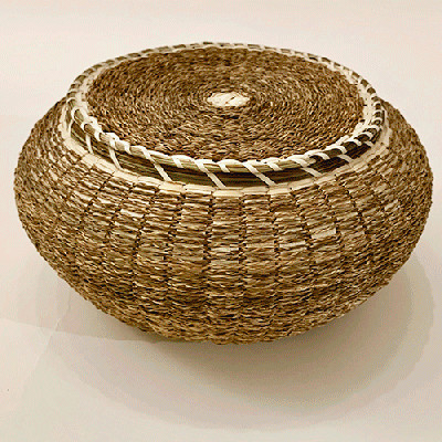 Image of short, wide basket woven with braided sweetgrass.