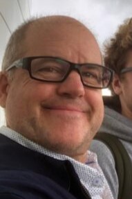 Image of Caucasian man with glasses smiling at camera.