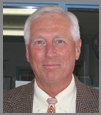 Image of older Caucasian man with white hair wearing a suit and tie.