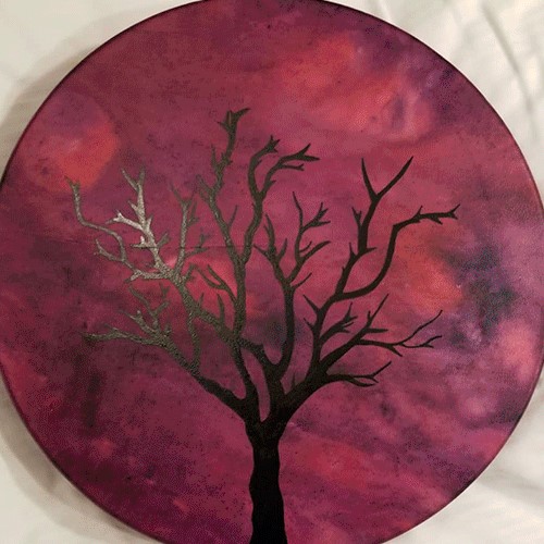 Image of drum with marbled red background and line drawing of a tree with no leaves.
