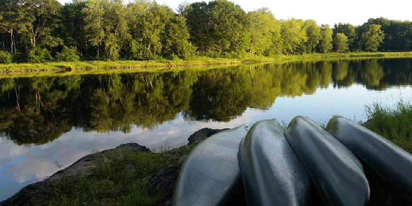 Image of canoes on shore with lake in background