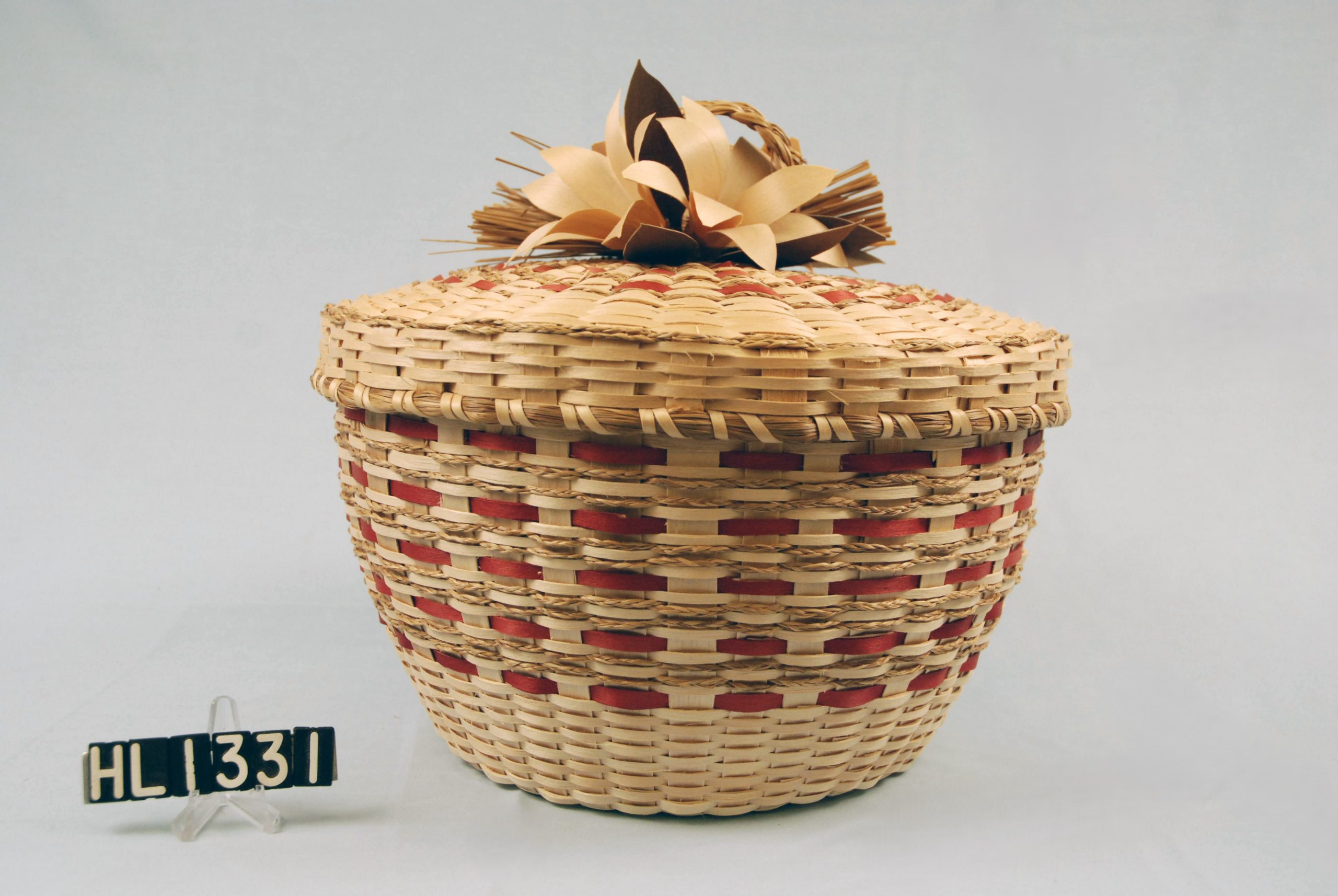 Basket with sweetgrass and red weaver details and flowers clustered on cover.