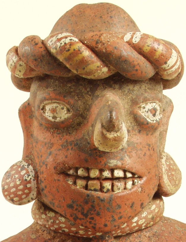Face of ceramic figure. Surface exhibits a generous scattering of dots and encrusted spots.